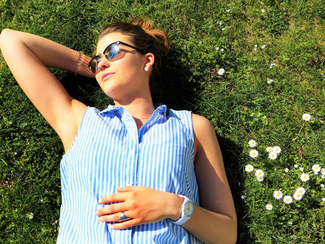 mulher deita na grama tomando sol